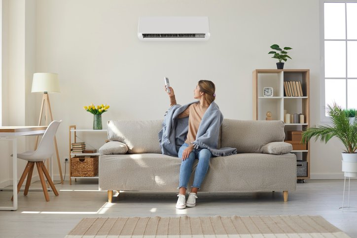 woman turning on ac unit with remote after having a home care maintenance plan appointment